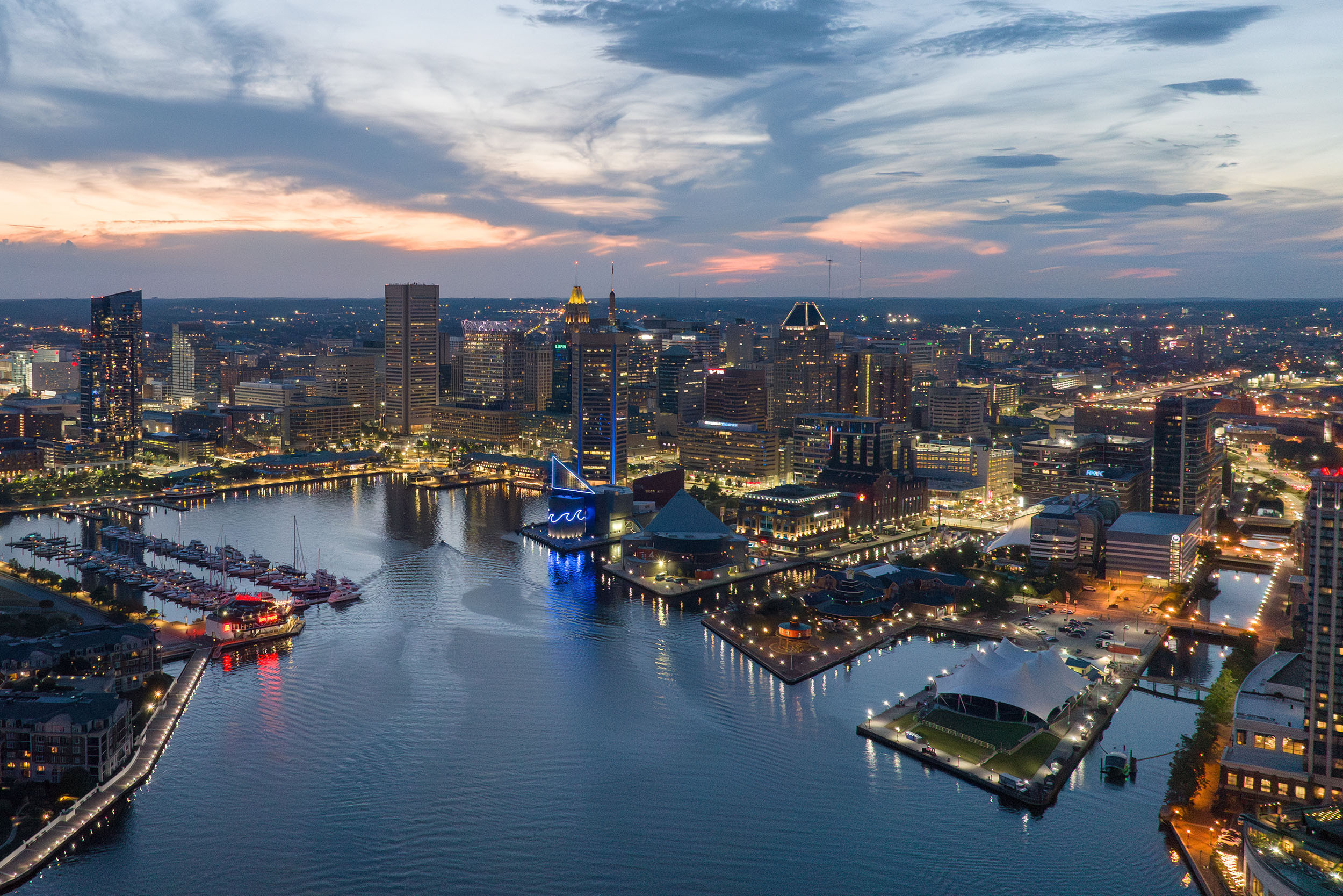 Aerial View of the Inner Harbor at Dusk With the City Lights Shining From the Perspective Over the Water